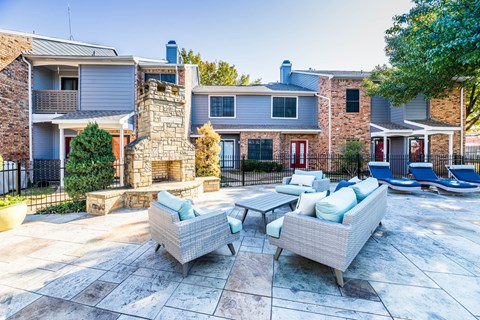 A patio with a stone fireplace and two couches.