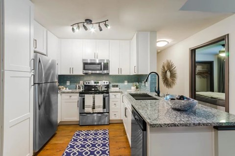 A modern kitchen with a granite countertop and stainless steel appliances. at Sunstone Village Apartments, Texas, 76208