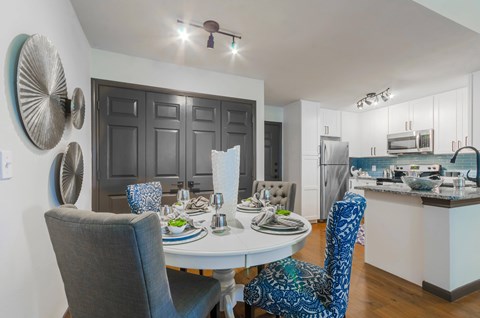 A modern dining room with a white table and blue chairs.
