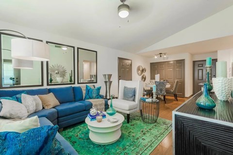 A living room with a blue couch and a green rug.
