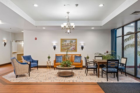 A living room with a large painting on the wall and a dining table with chairs around it.