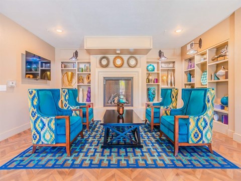 A living room with blue chairs and a fireplace.
