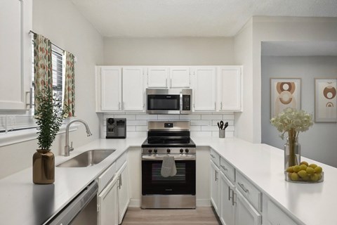 A modern kitchen with white cabinets and stainless steel appliances.