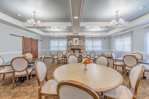 Community dining room with fireplace and tables at Schuyler Commons Apartments, Utica, 13502