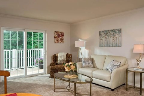 A living room with a white couch, a glass table, and a painting on the wall.