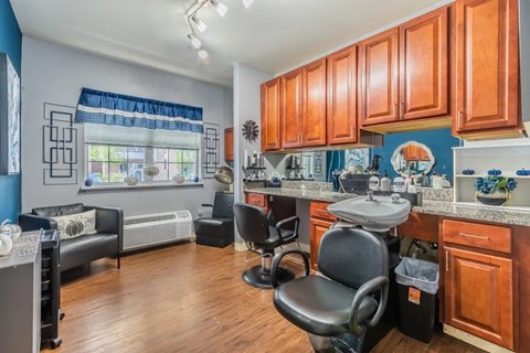 A kitchen with wooden cabinets and a black chair.