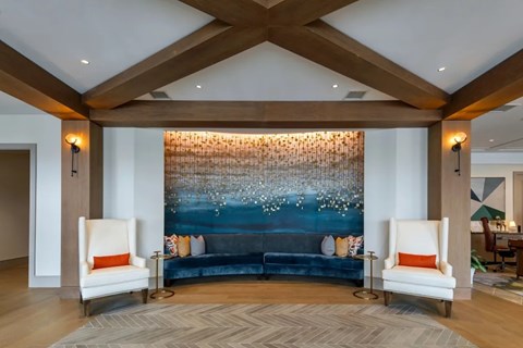 A living room with a blue couch and two white chairs.