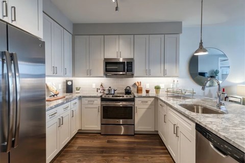 A modern kitchen with white cabinets and stainless steel appliances.