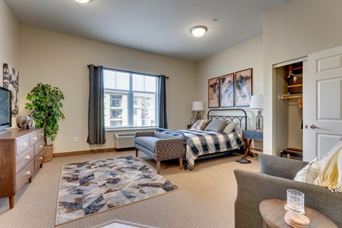 A bedroom with a large bed and a window with curtains.