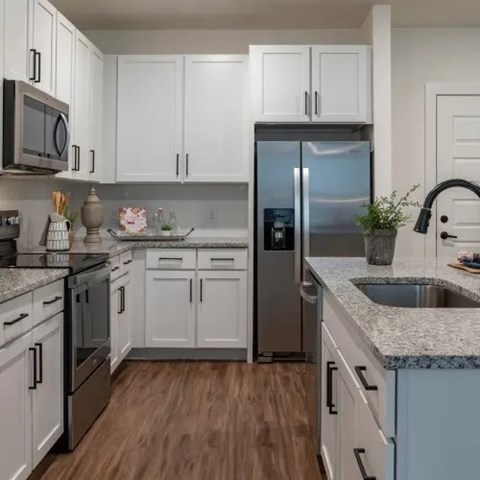 A kitchen with white cabinets and a stainless steel refrigerator.