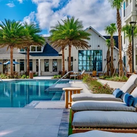 A poolside area with lounge chairs and a table. at Atwater at Nocatee Apartments, Florida, 32081