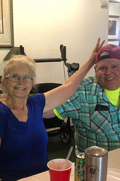 A man and a woman are posing for a picture with a can of beer on the table.