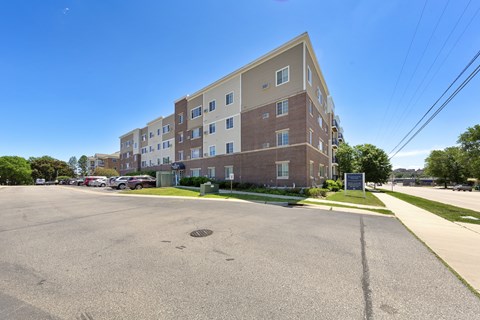 A large parking lot in front of a multi-story apartment building.