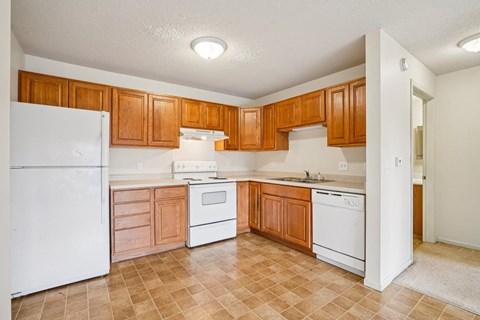 A kitchen with white appliances and wooden cabinets.