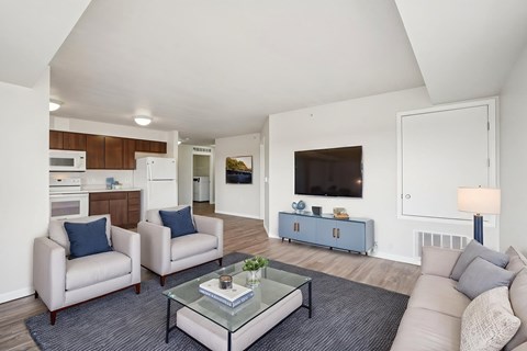 A living room with a glass coffee table and two chairs.