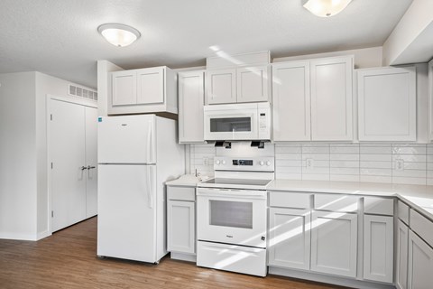 A white kitchen with a refrigerator, oven, and microwave.
