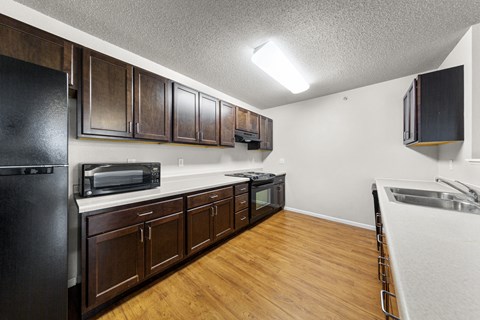 A kitchen with dark wood cabinets and a black refrigerator.
