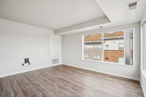 A room with a window showing a view of a building.