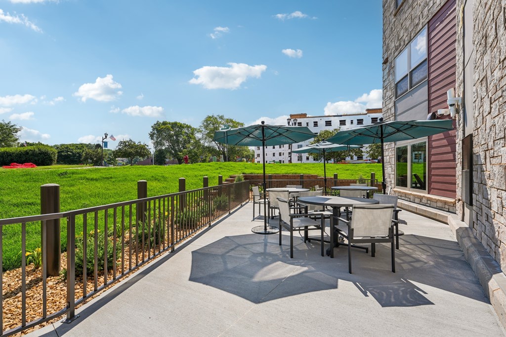 A patio with a table and chairs is surrounded by a metal fence.