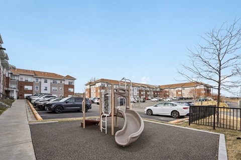 A playground with a slide and a car parked in the background.