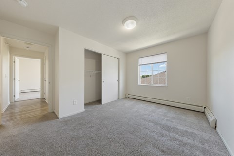 A spacious room with a carpeted floor and a window showing a building outside.