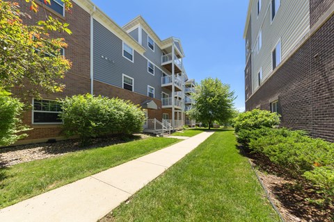 A long concrete walkway separates two apartment buildings.