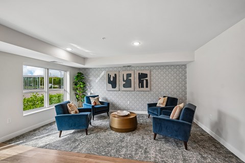 A living room with blue chairs and a grey rug.