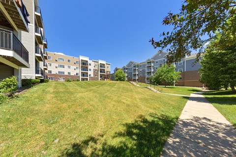 A sunny day at a grassy area in front of apartment buildings.