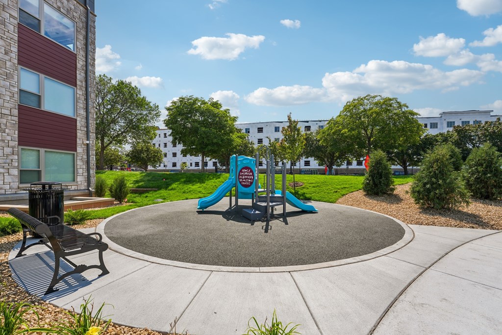 A playground with a slide and a bench in the foreground.