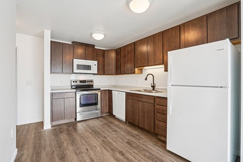 A white refrigerator is in the corner of a kitchen with wooden cabinets.