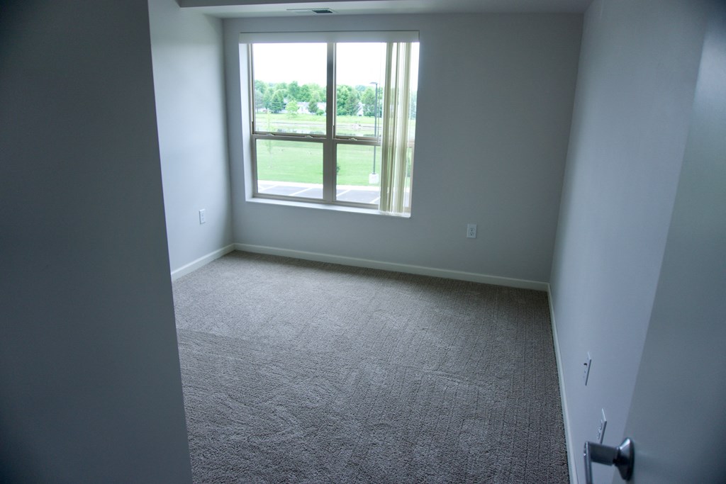 an empty room with a window and carpet