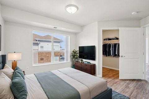 A bedroom with a large bed and a window overlooking a house.