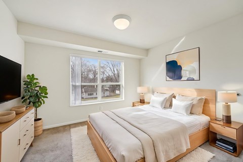 A well-lit bedroom with a large bed and a television.