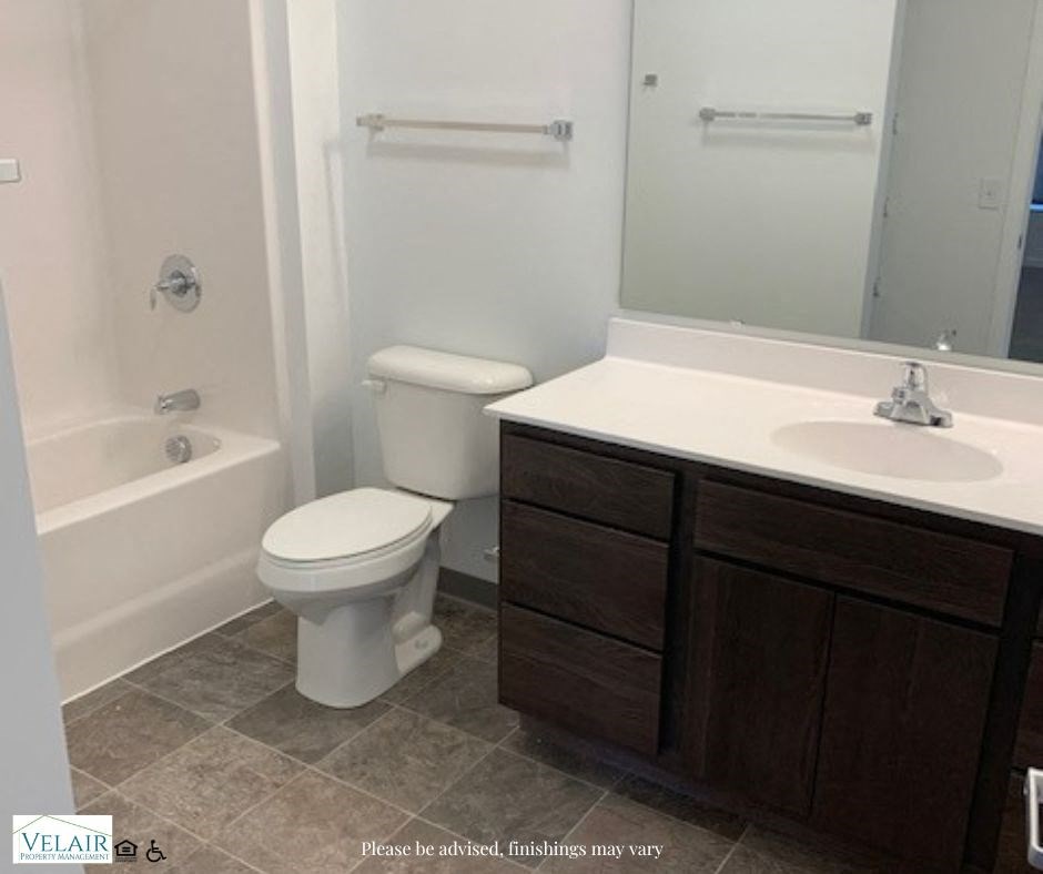 A white toilet sits in a bathroom next to a sink.