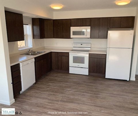 A kitchen with white appliances and brown cabinets.