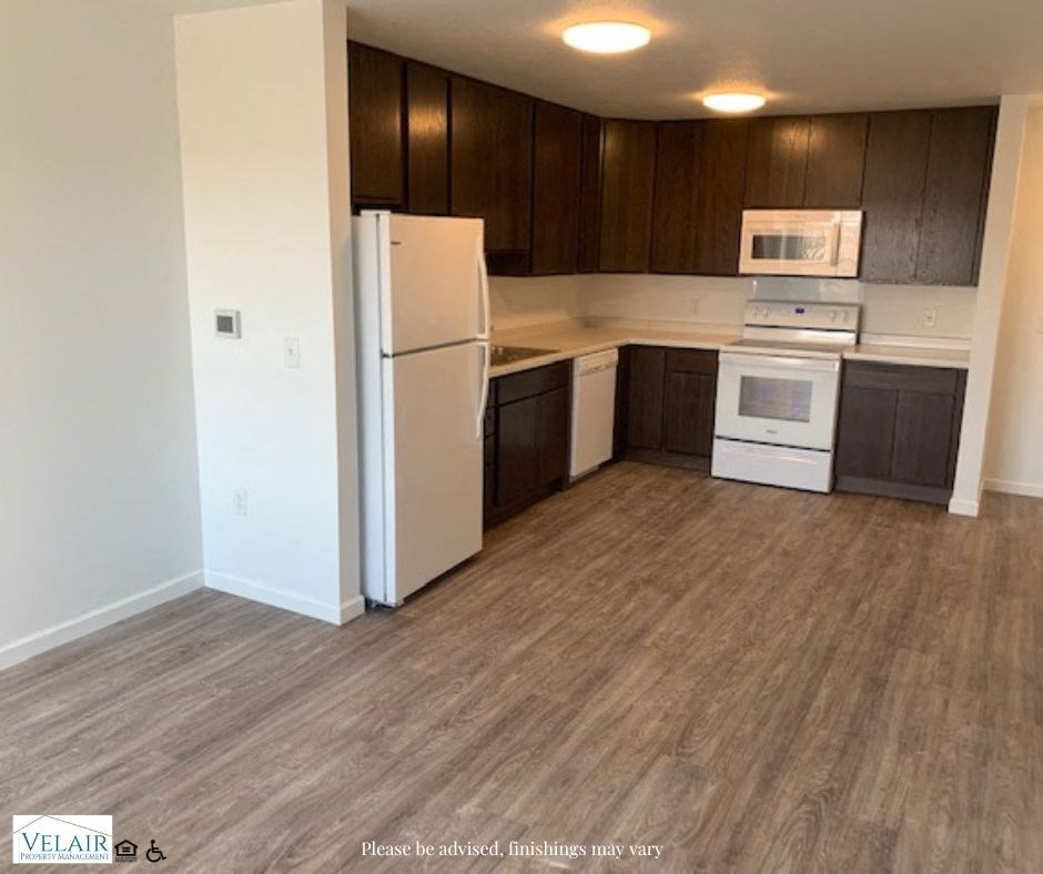 A kitchen with a white fridge, microwave, and oven.