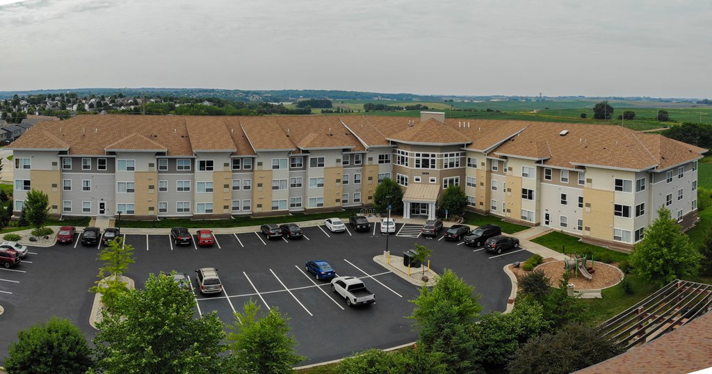 A parking lot in front of a large apartment complex.