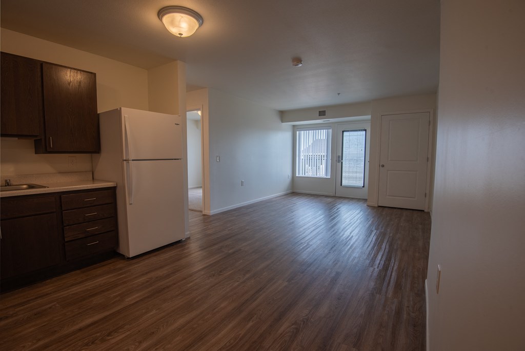 an empty kitchen and living room with a refrigerator and microwave