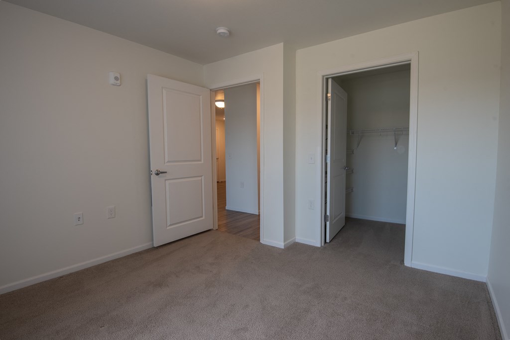 an empty bedroom with a closet and a door to a hallway