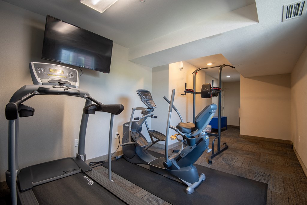 a gym with two treadmills and a tv in the corner