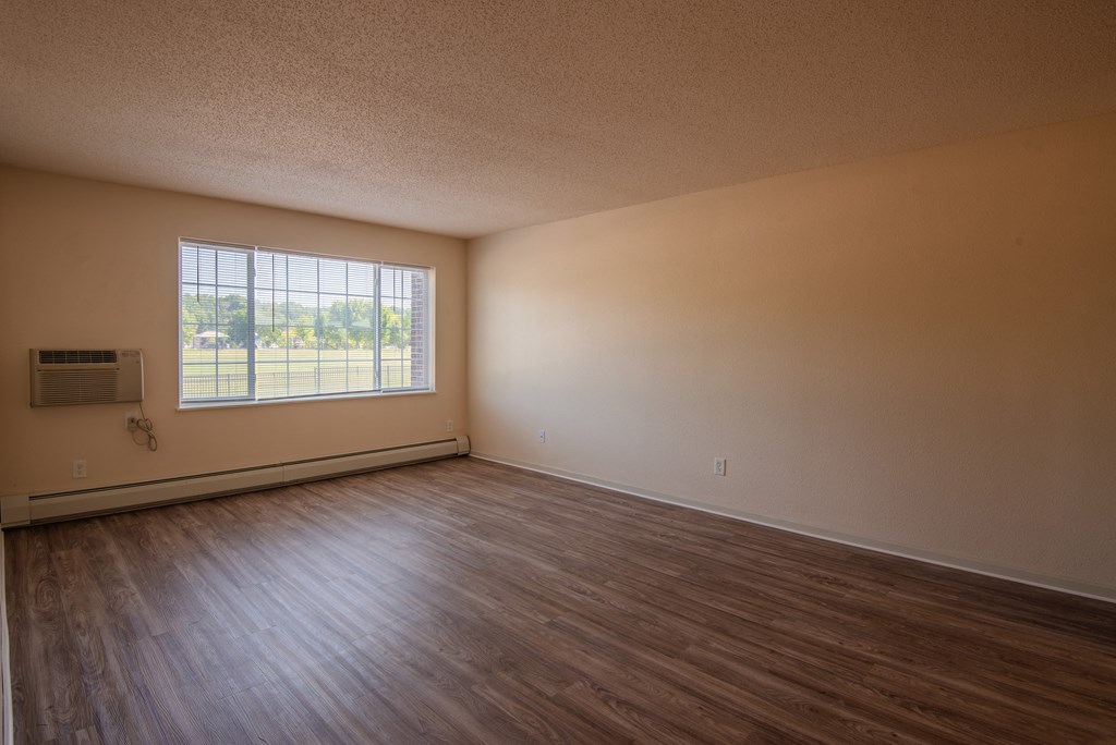 an empty living room with wood floors and a window