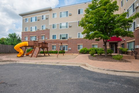 a playground in front of an apartment building with a yellow slide