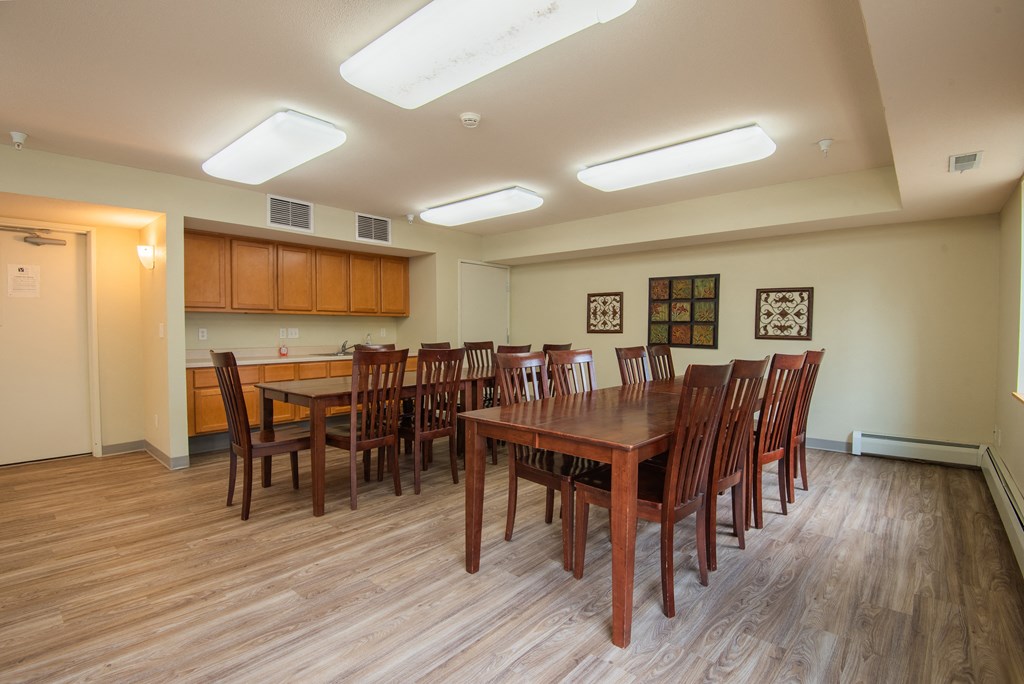 a dining room with wooden tables and chairs and a kitchen