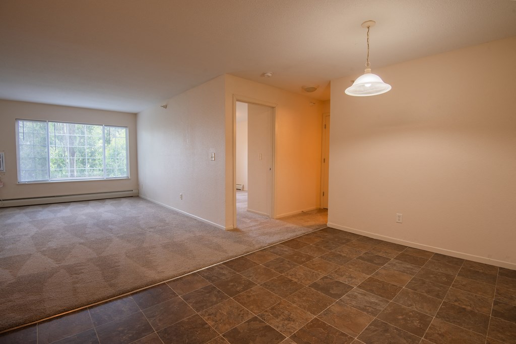 the living room and dining room of an empty house with a large window and t