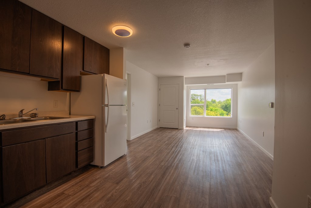 an empty kitchen and living room with a refrigerator and sink