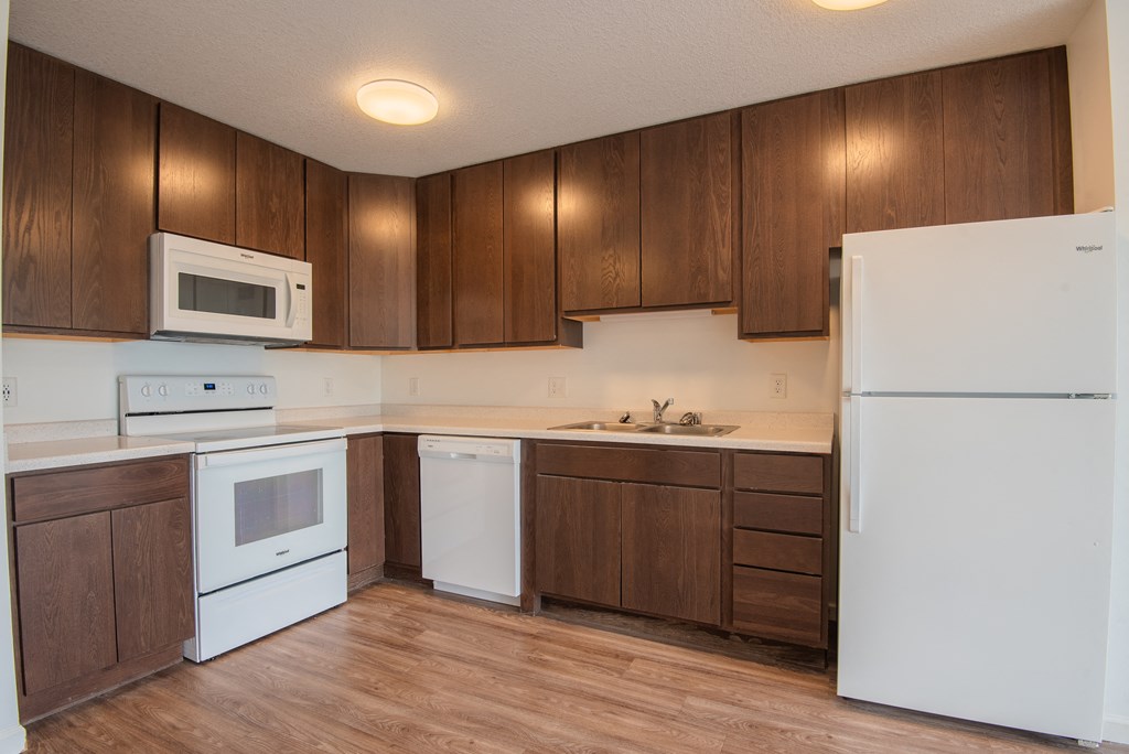 an empty kitchen with white appliances and wooden cabinets
