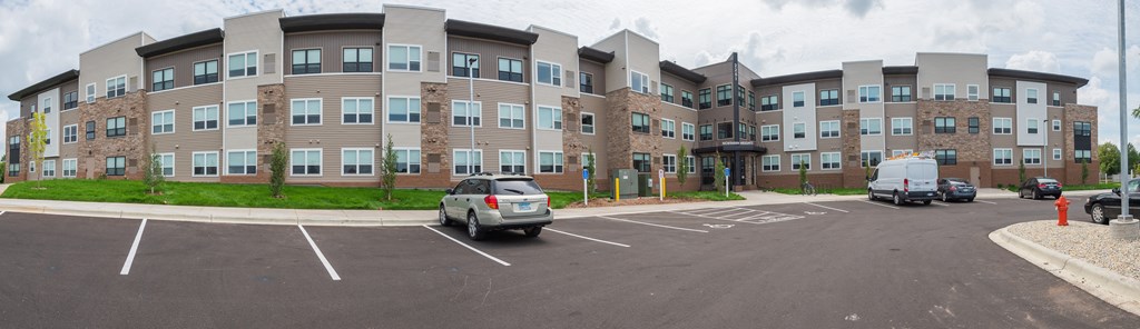 A parking lot in front of a large apartment building.