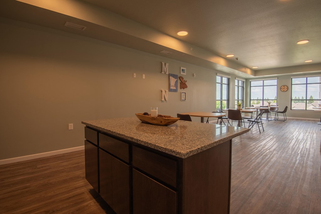 A kitchen with a granite countertop and wooden floors.