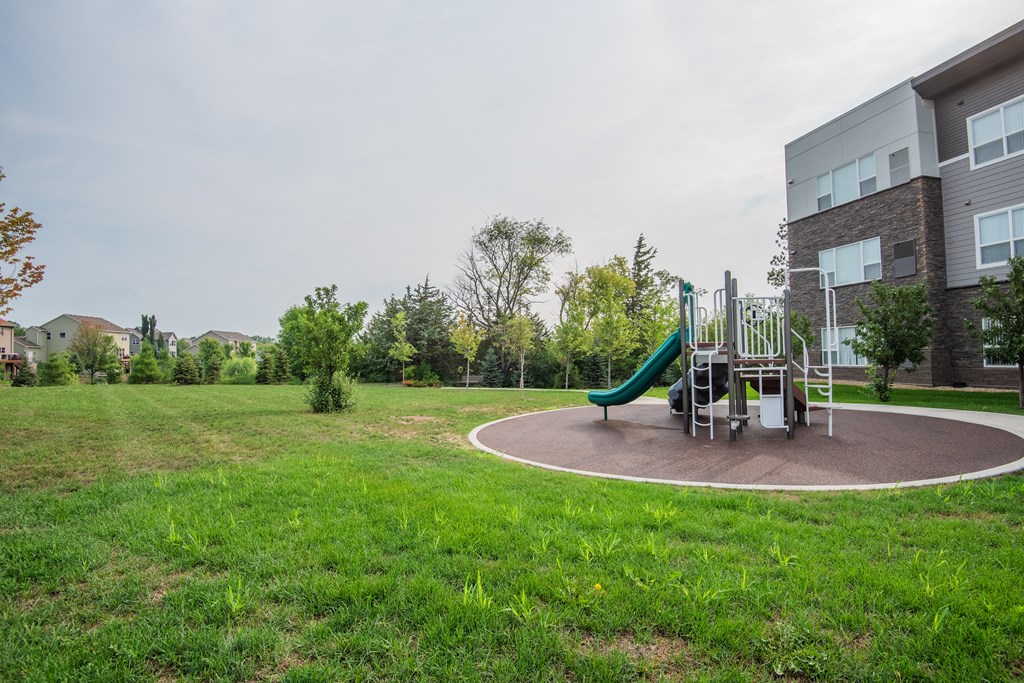 A playground with a green slide and a red swing set.
