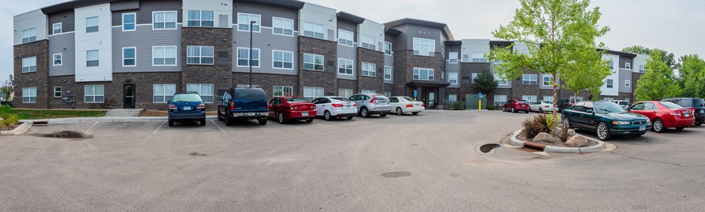 A parking lot with cars and apartment buildings in the background.